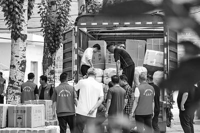 8月9日，在榆中县第三中学安置点，工作人员和志愿者搬运物资。新华社记者 郎兵兵摄